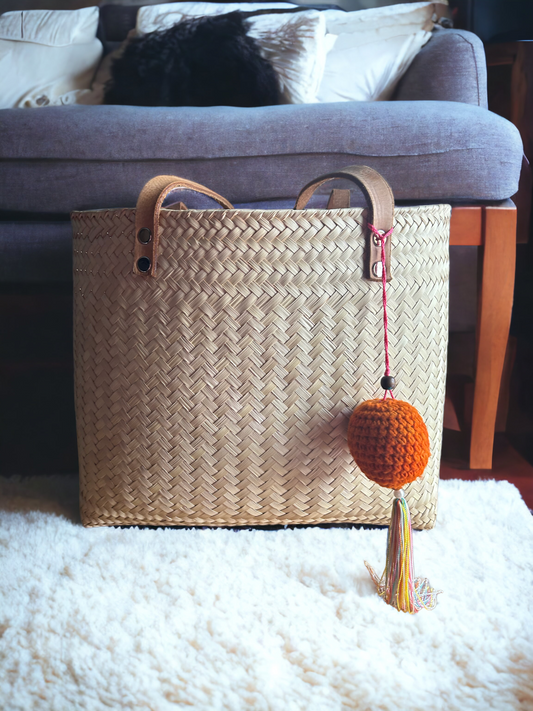 Handwoven chic artisan palm leaf tote bag with a whimsical crochet pom pom, exuding elegance and charm